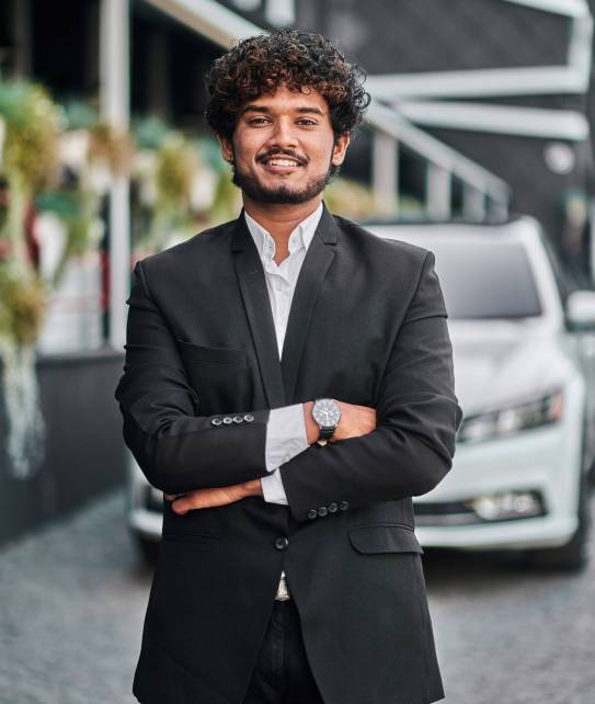 Indian businessman in the background of his white car.